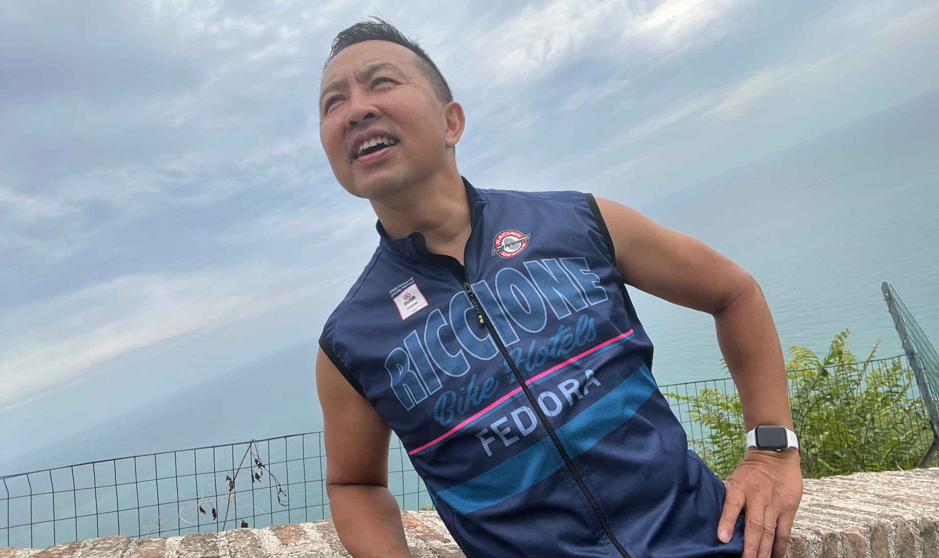 Eric Mallari in a Riccione Bike Hotels cycling jersey, looking out over the Adriatic Sea in Riccione, Italy.